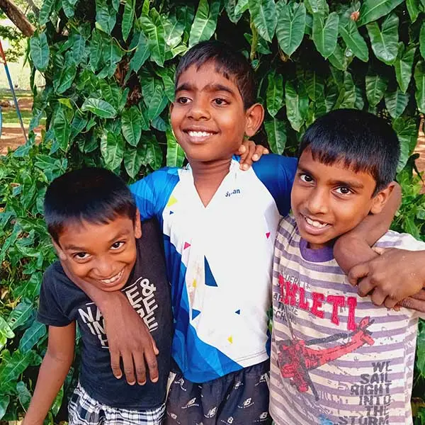 Drie jongens hebben plezier en slaan de arm om elkaars schouder.