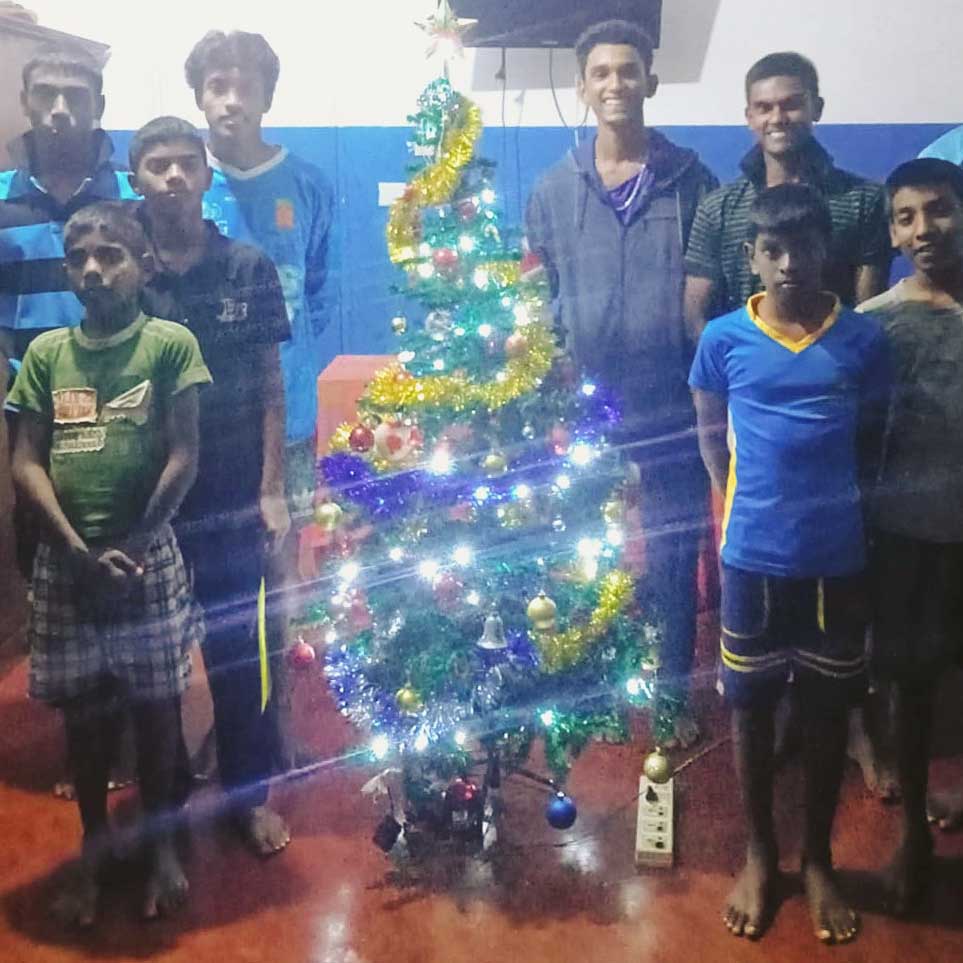 jongens staan bij de versierde kerstboom